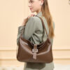 Side profile of a woman carrying a glossy brown leather hobo bag over her shoulder, showcasing its elegant shape and buckle detail.