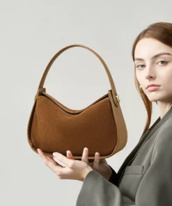 Brown Suede Handbag — curved hobo shoulder bag with short top handle and gold hardware on a light grey background